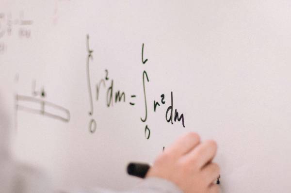 Person writing math equations on a board
