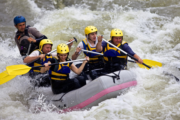 Group of people river rafting in rapid water.
