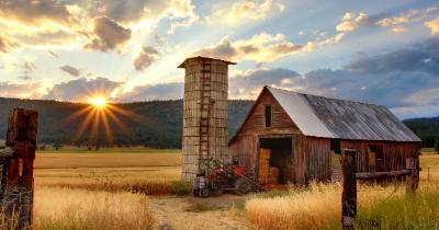 Old farm building and silo with a sunrise over the mountains in the background